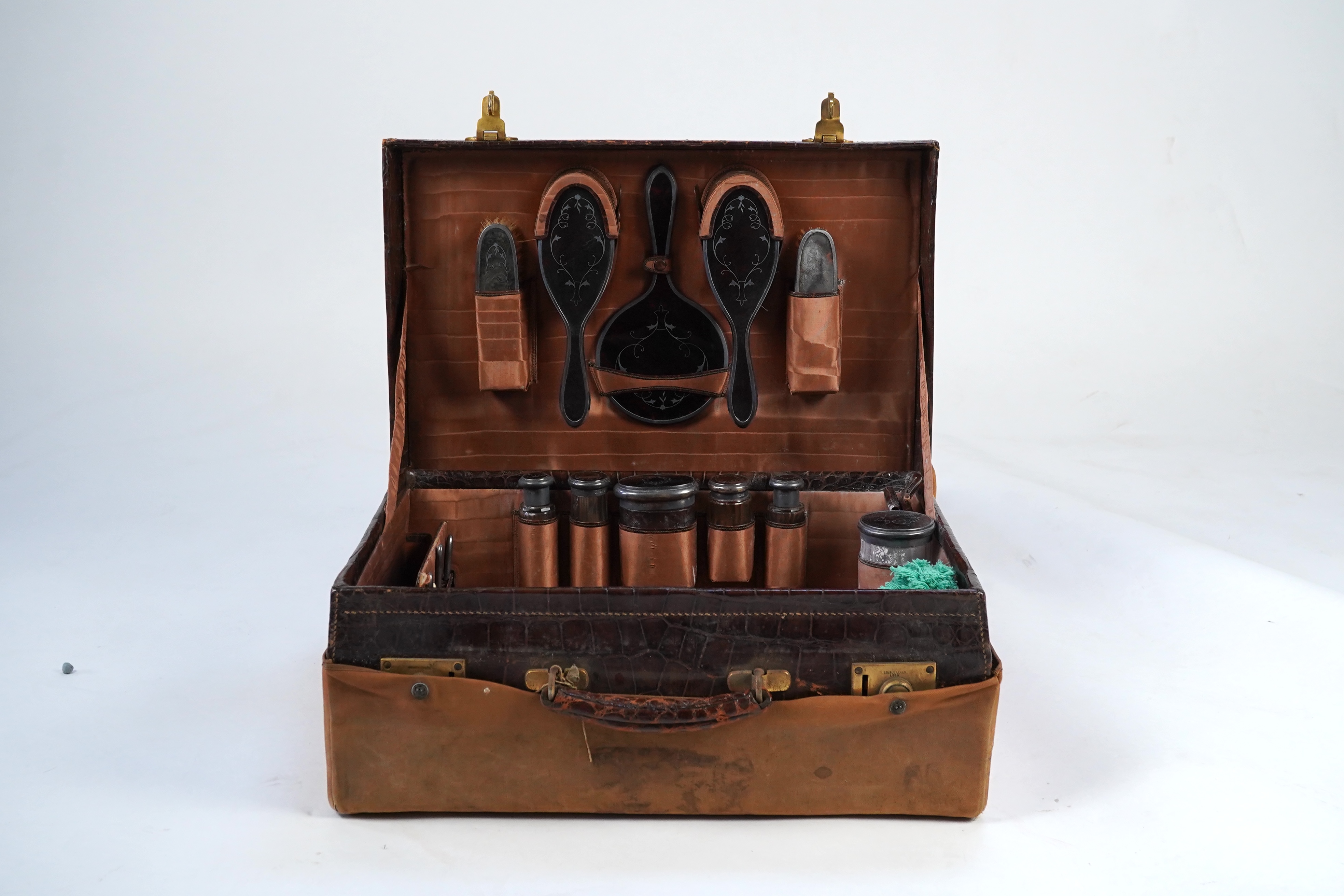 A George V crocodile skin travelling toilet case, containing twelve silver and tortoiseshell mounted accoutrements, by Collet & Anderson